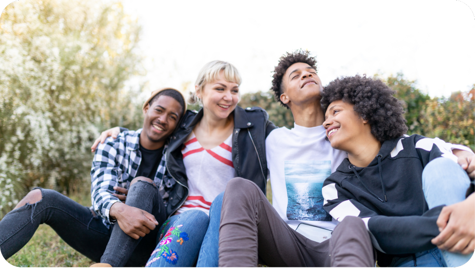 Four happy young people outdoors leaning on each other. 