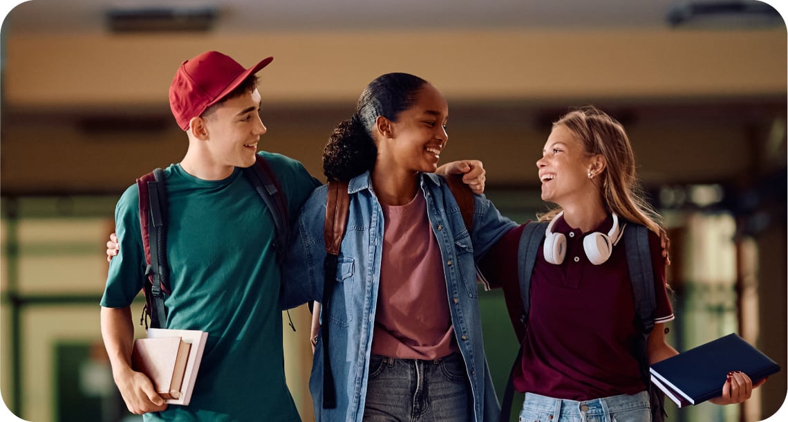 Three young people happily walking through a school hallway. 
