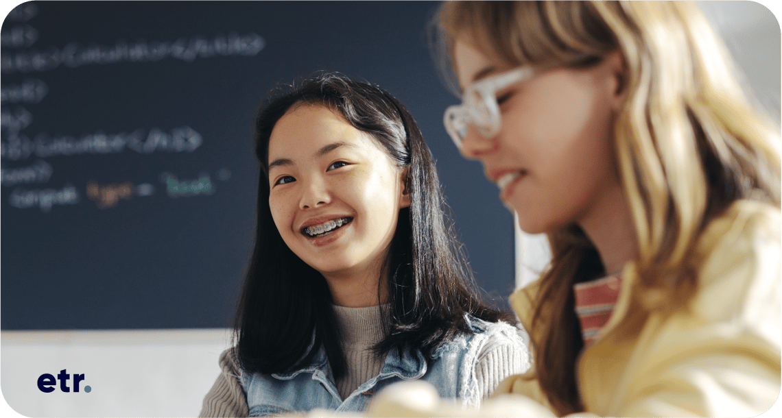 Two young people in the classroom smiling. 